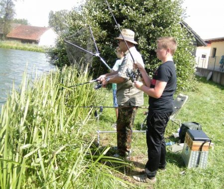 Angelrute und Kescher fest in der Hand. Jeden Augenblick könnte ein Fisch anbeißen!